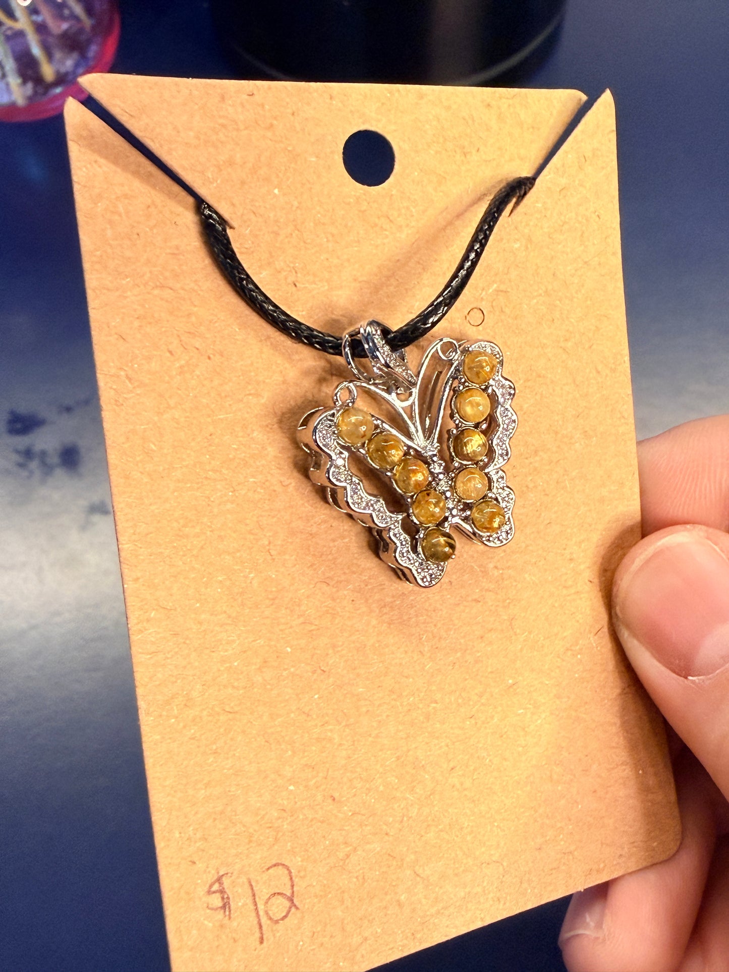 Butterfly shaped crystal pendant being held on a card by a hand