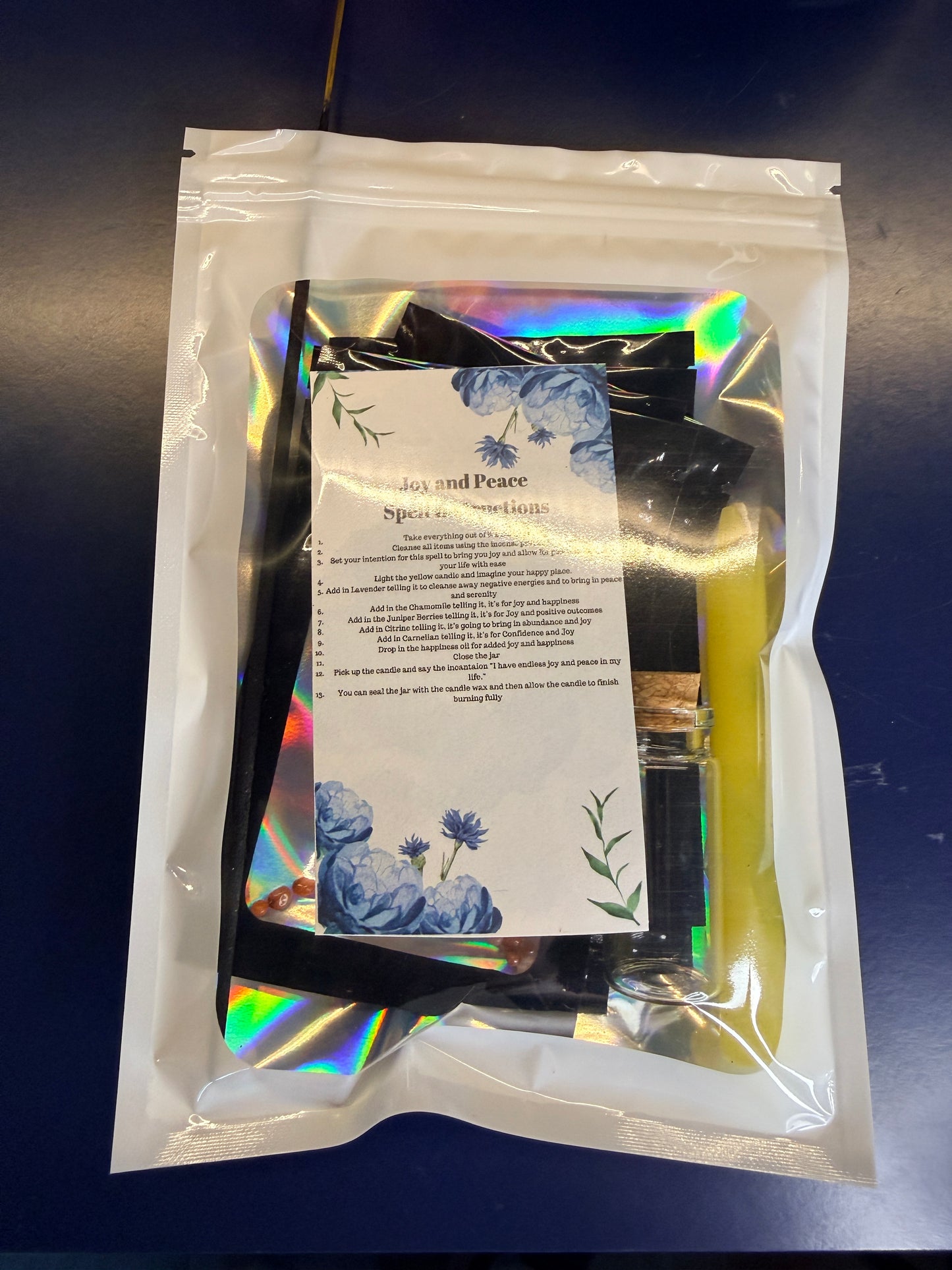 White plastic bag with a clear window showing a piece of paper and yellow candle against a blue background