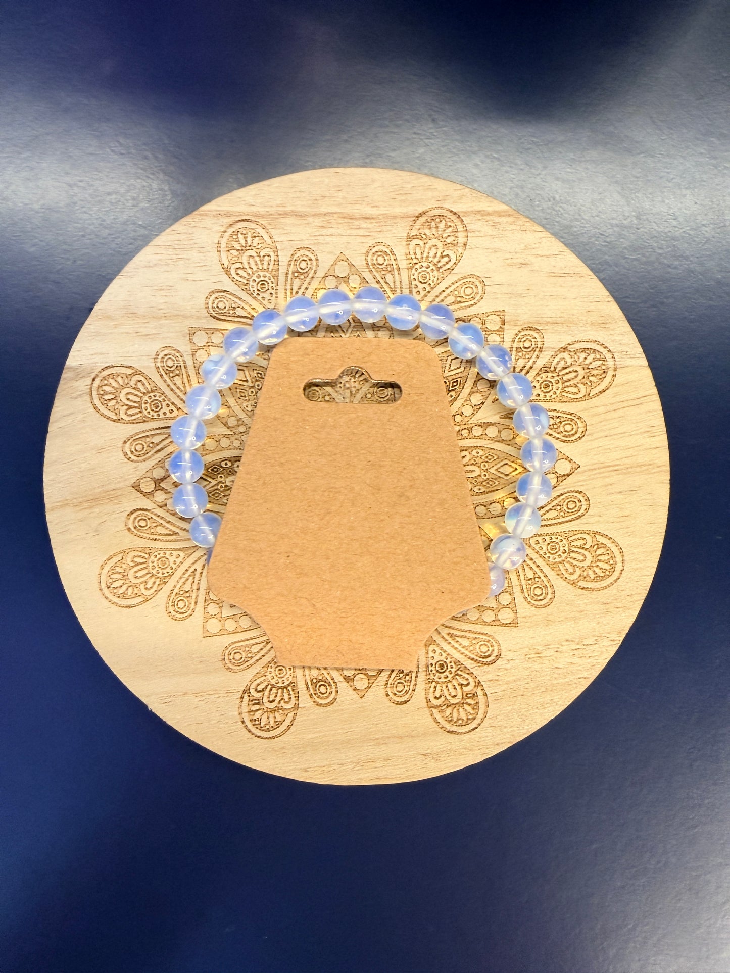 Clear beaded crystal bracelet on a decorative wooden coaster against a blue background