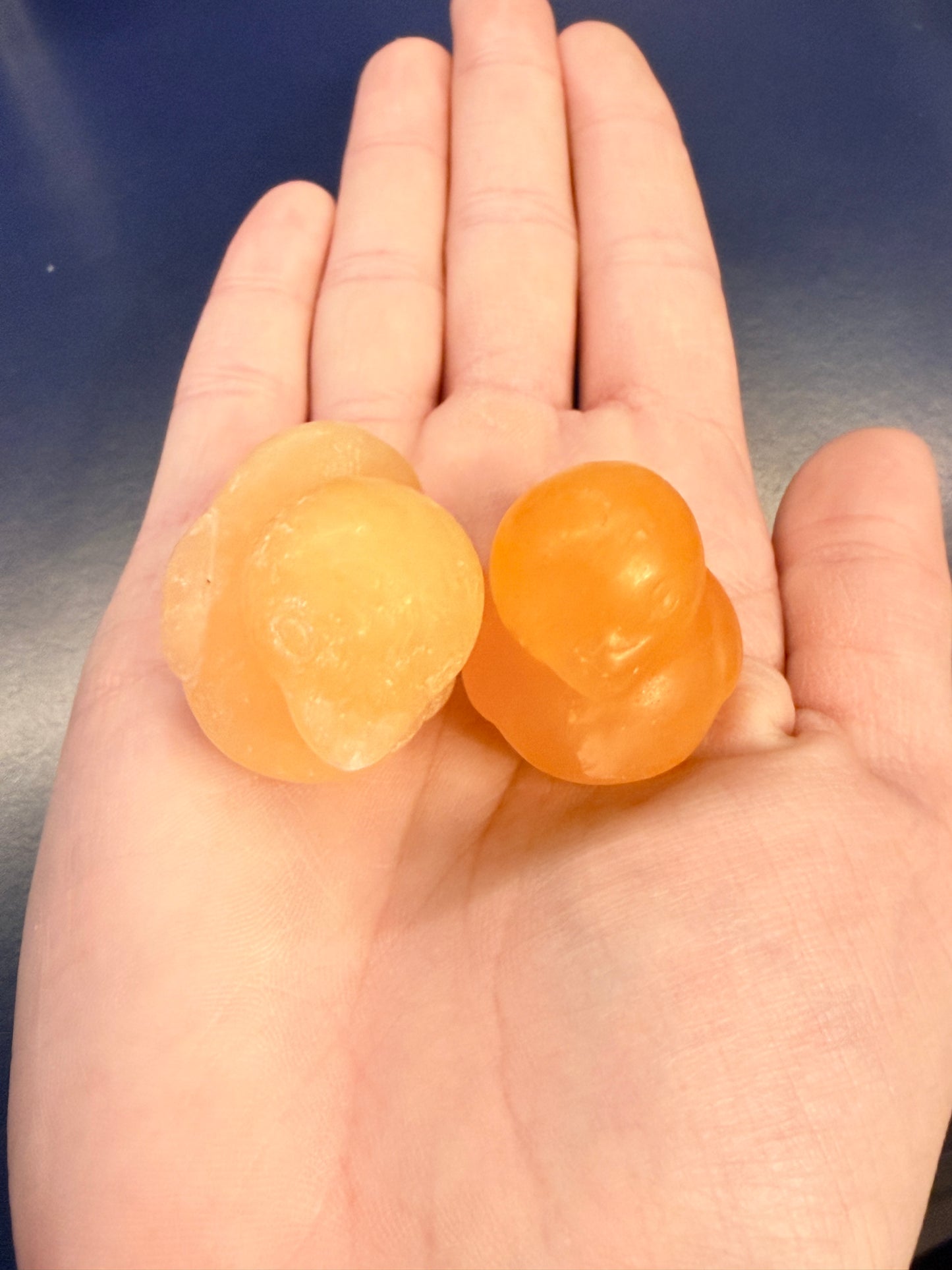 Two orange crystal ducks sitting on an outstretched hand against a blue background