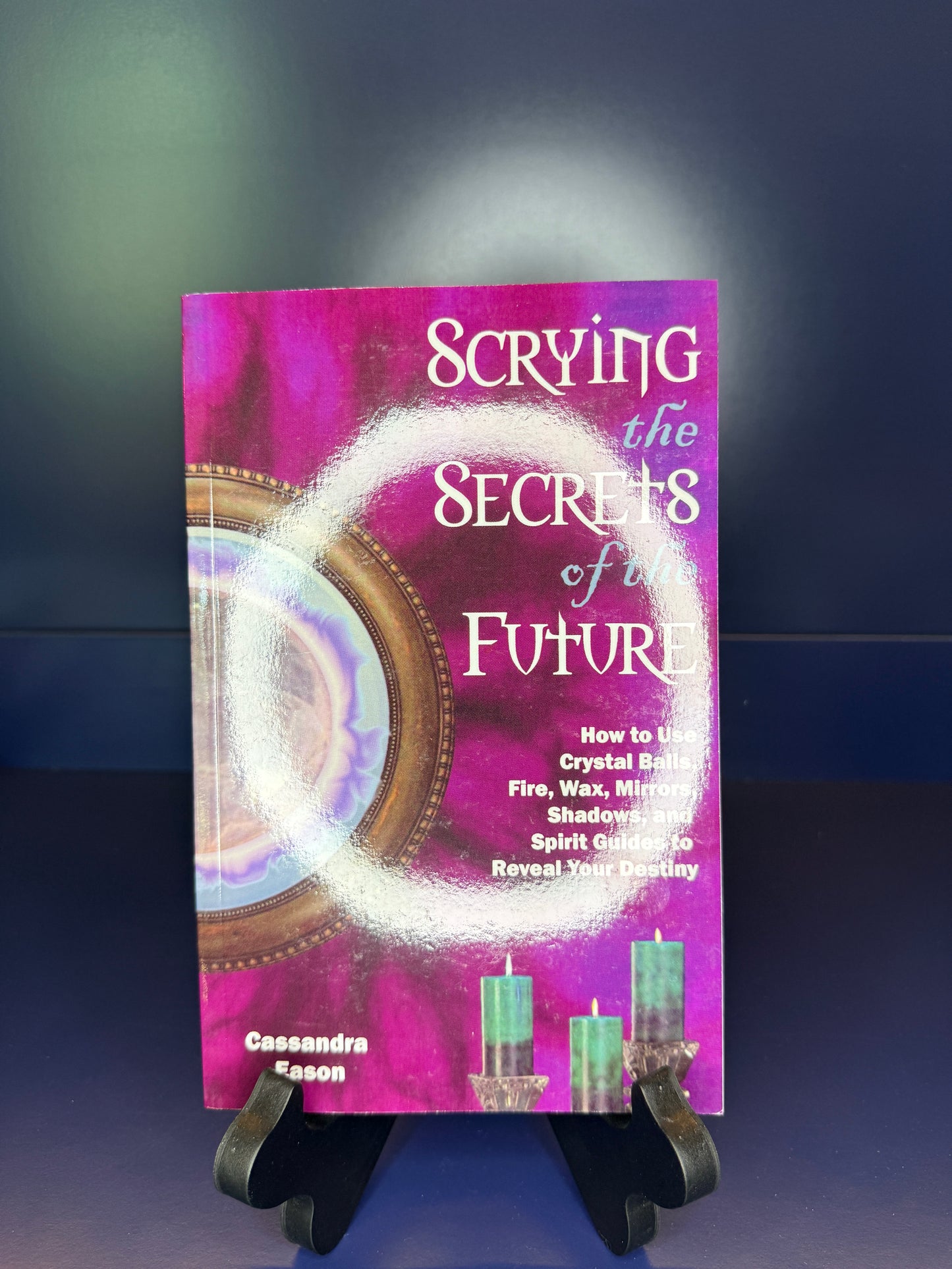 Book titled 'Scrying the Secrets of the Future' by Cassandra Eason on a stand on a blue background