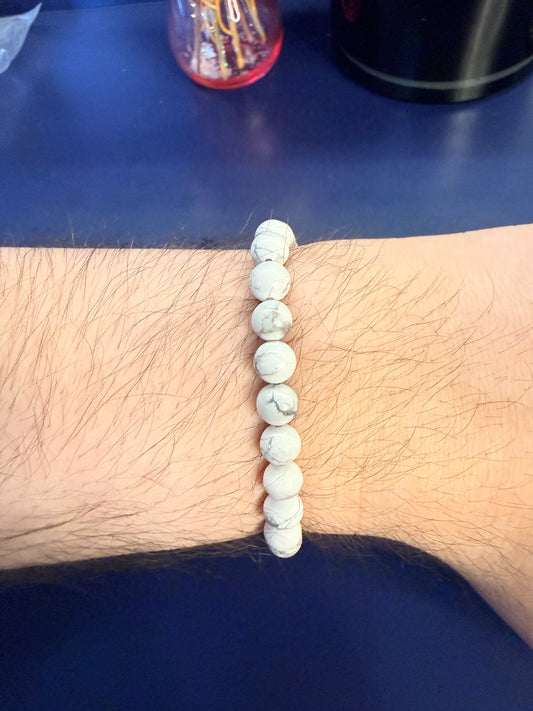 White beaded crystal bracelet on a wrist with a blue background