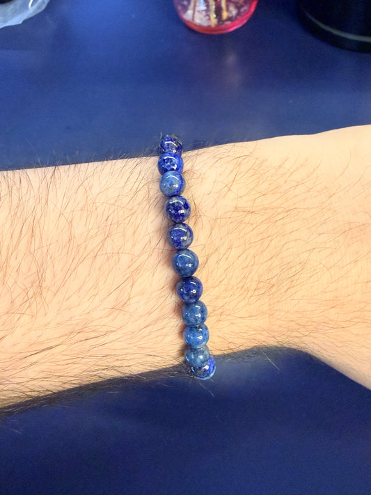 Blue beaded crystal bracelet on a wrist against a blue background