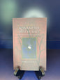 Book titled 'Advanced Witchcraft' by Patricia Telesco on a stand with a gradient blue background