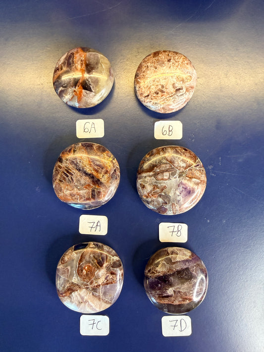 Six Purple and amber alien amethyst palmstones on a blue background