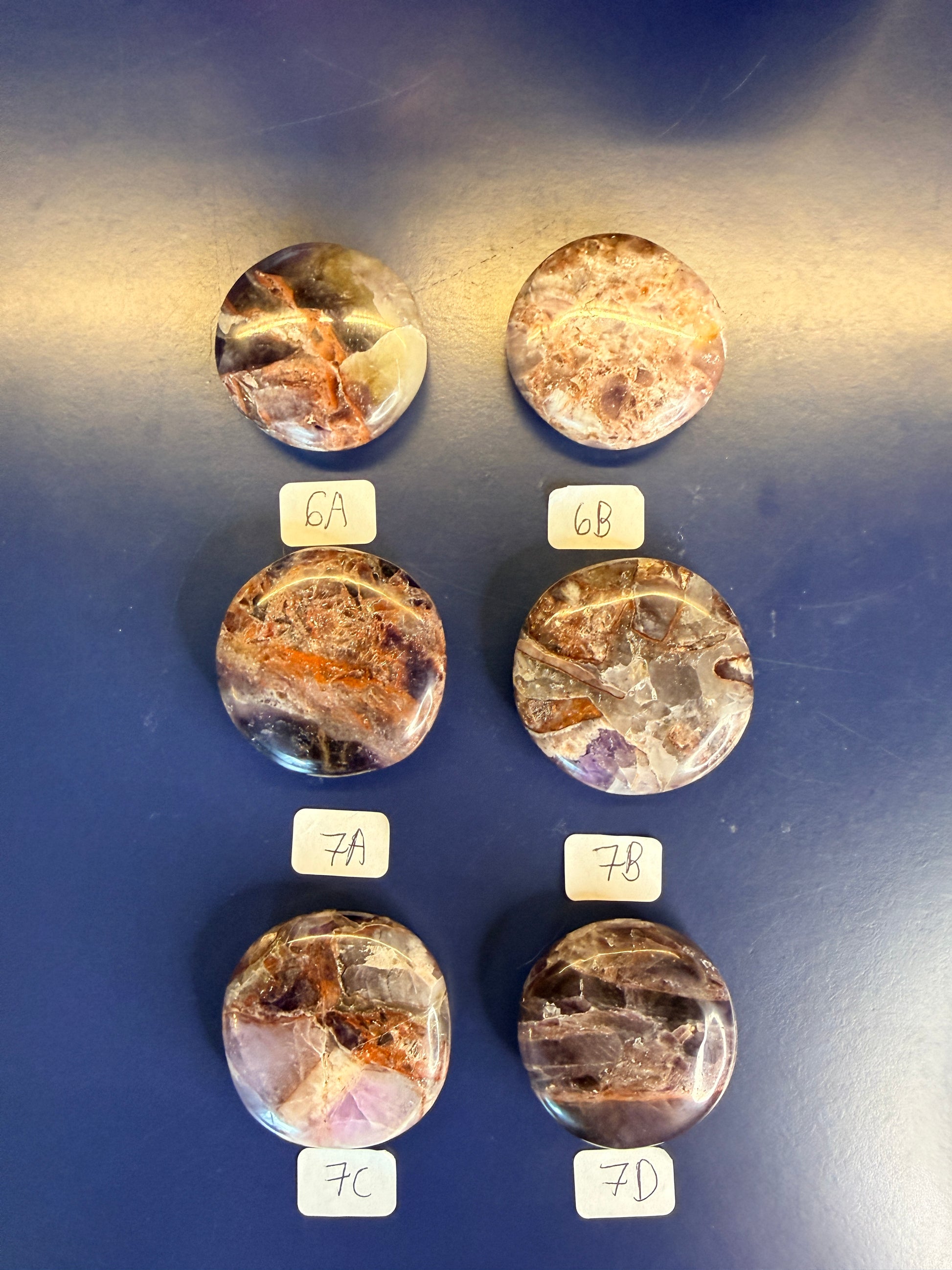 Six Purple and amber alien amethyst palmstones on a blue background