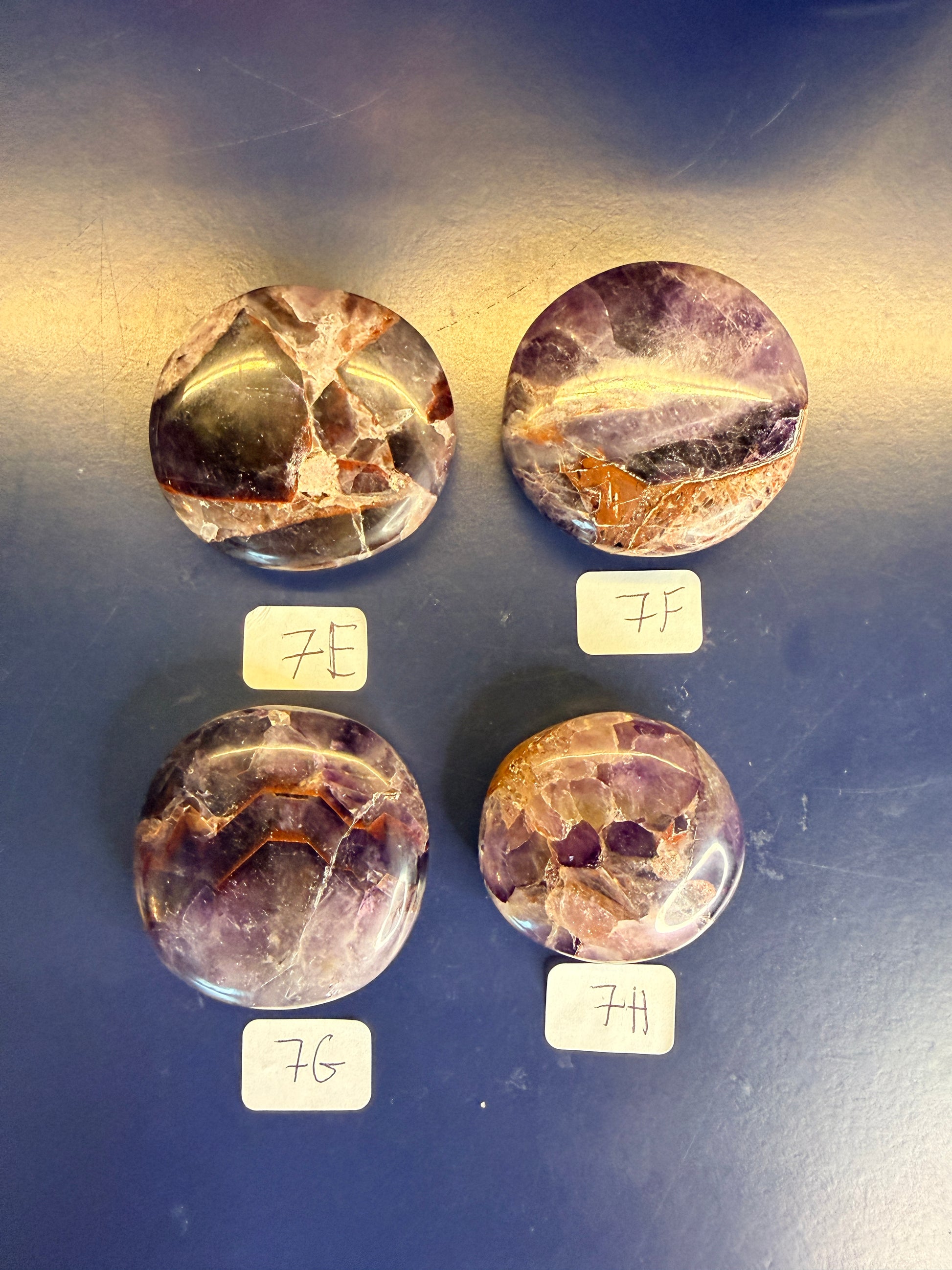 Four purple and amber alien amethyst palmstones on a blue background