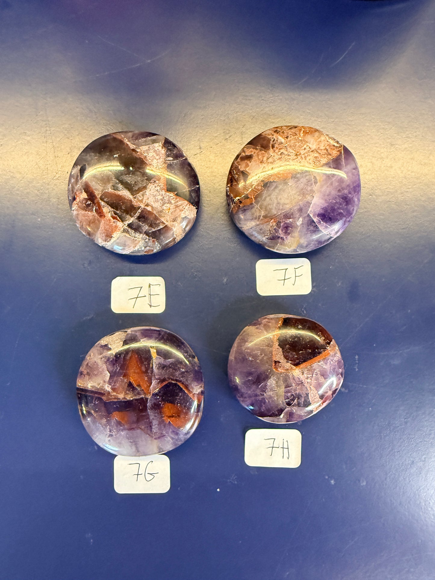 Four purple and amber alien amethyst palmstones on a blue background