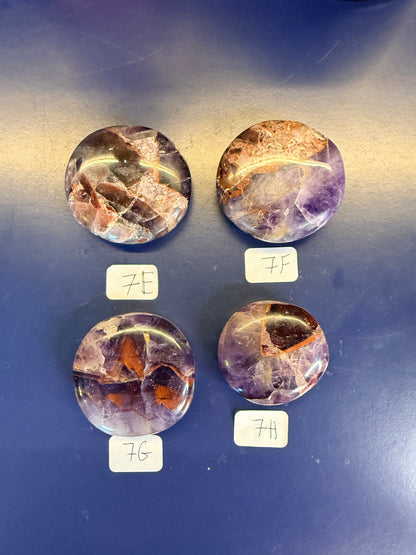Four purple and amber alien amethyst palmstones on a blue background