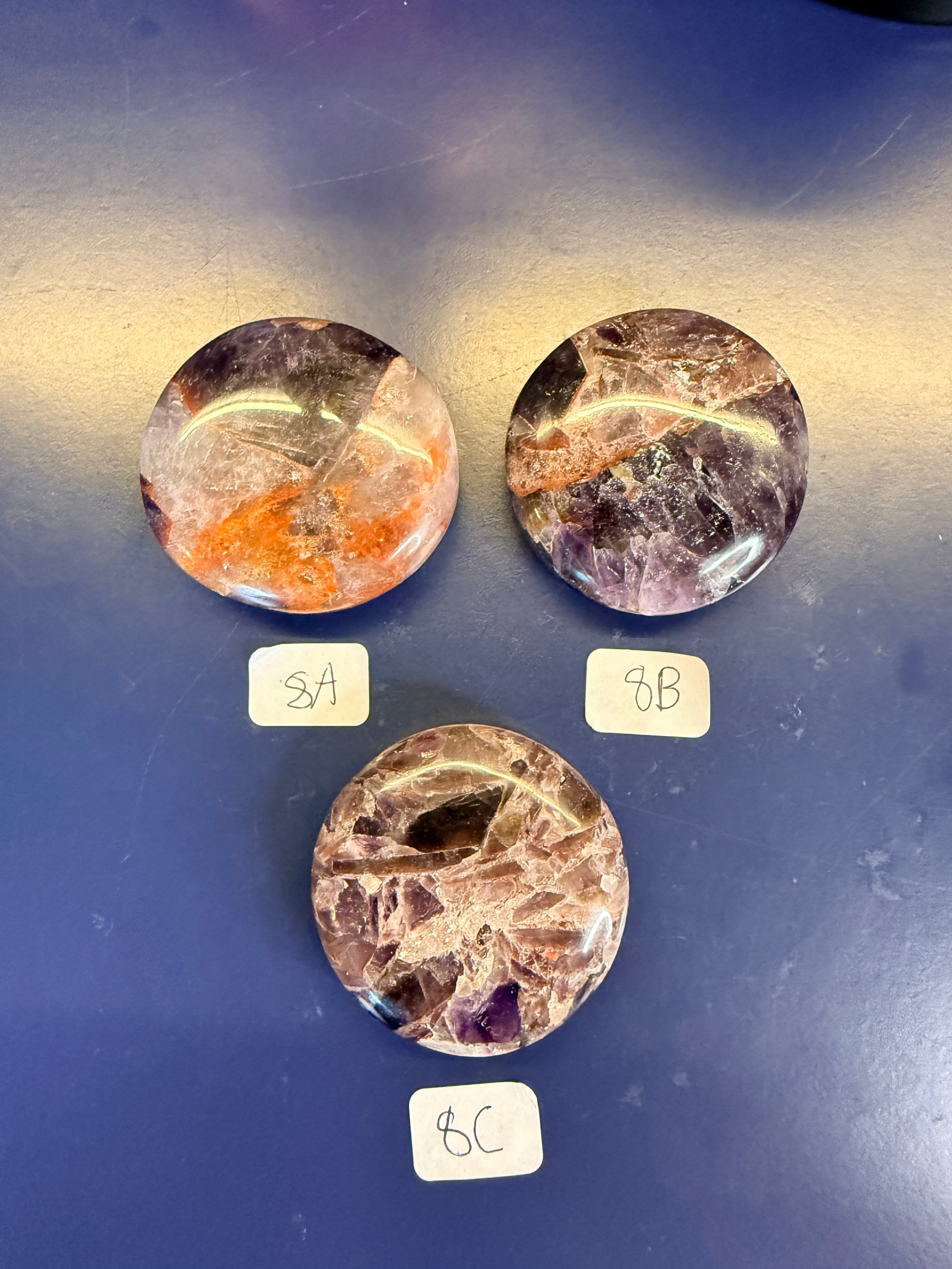 Three purple and amber alien amethyst palmstones on a blue background