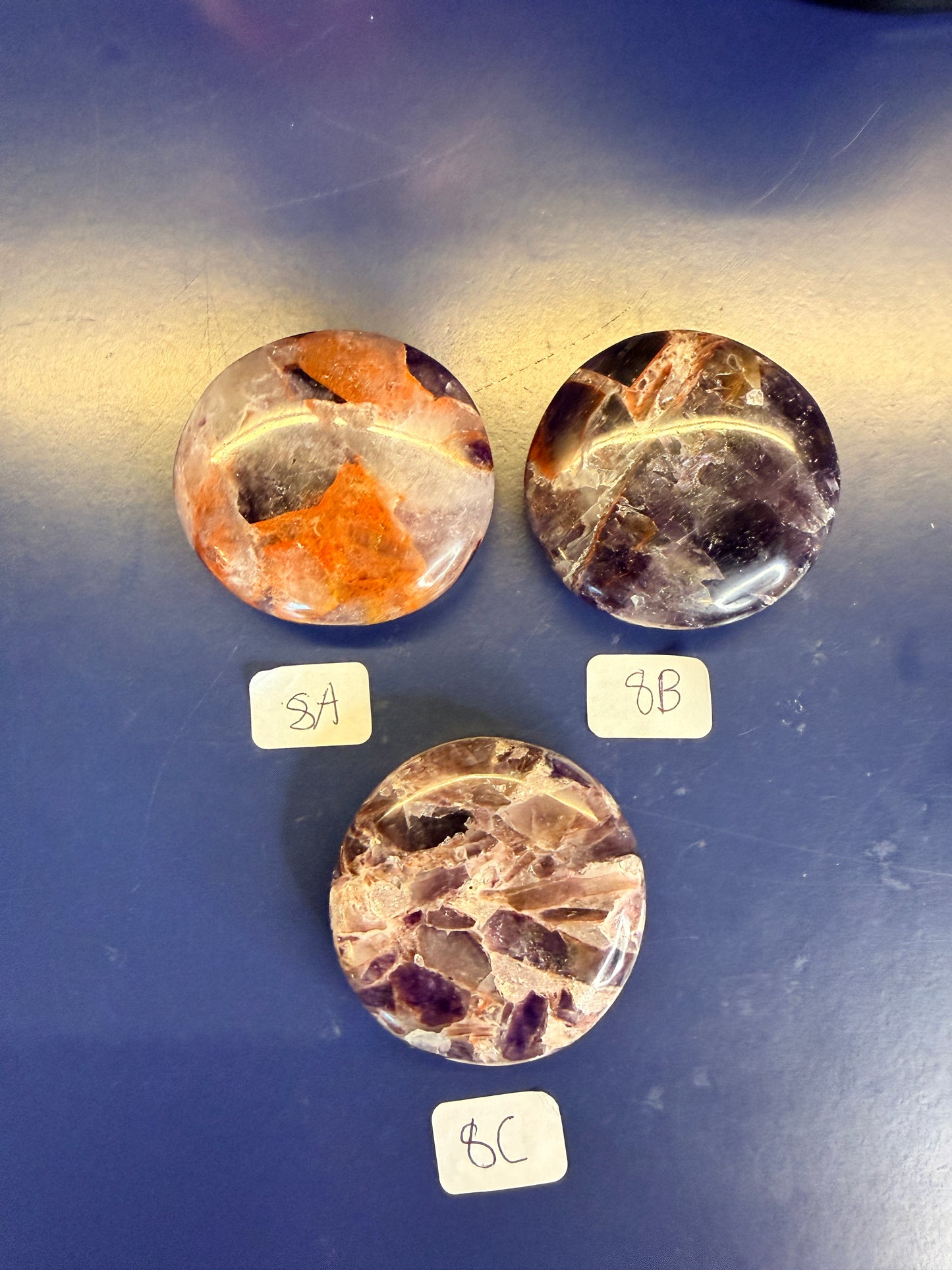 Three purple and amber alien amethyst palmstones on a blue background