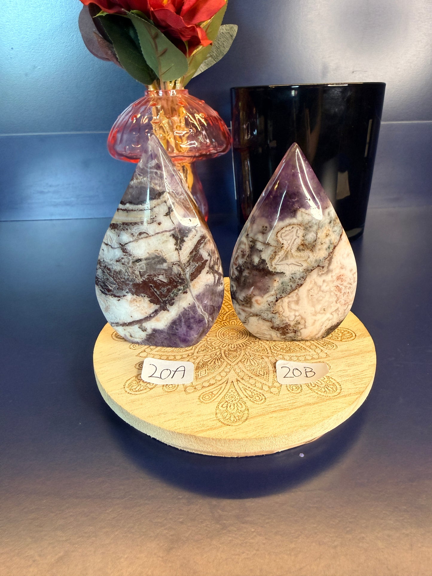 Two amethyst crystal freeforms on a wooden coaster with numbers 17 and 18, in front of a vase and jar