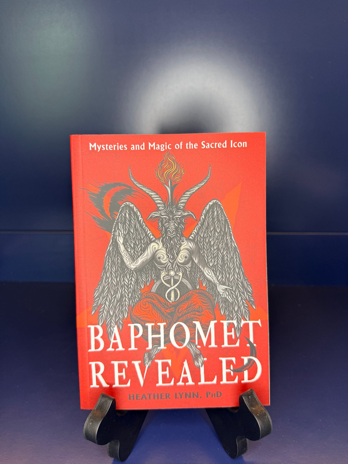 Book titled 'Baphomet Revealed' on a stand against a dark background
