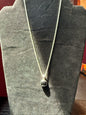Sterling silver chain resting on a black velvet jewelry stand holding a square black onyx pendant