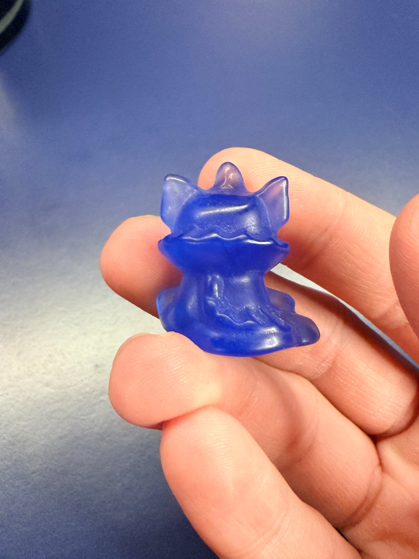 Hand holding a blue opalite vaporeon crystal against a blue background