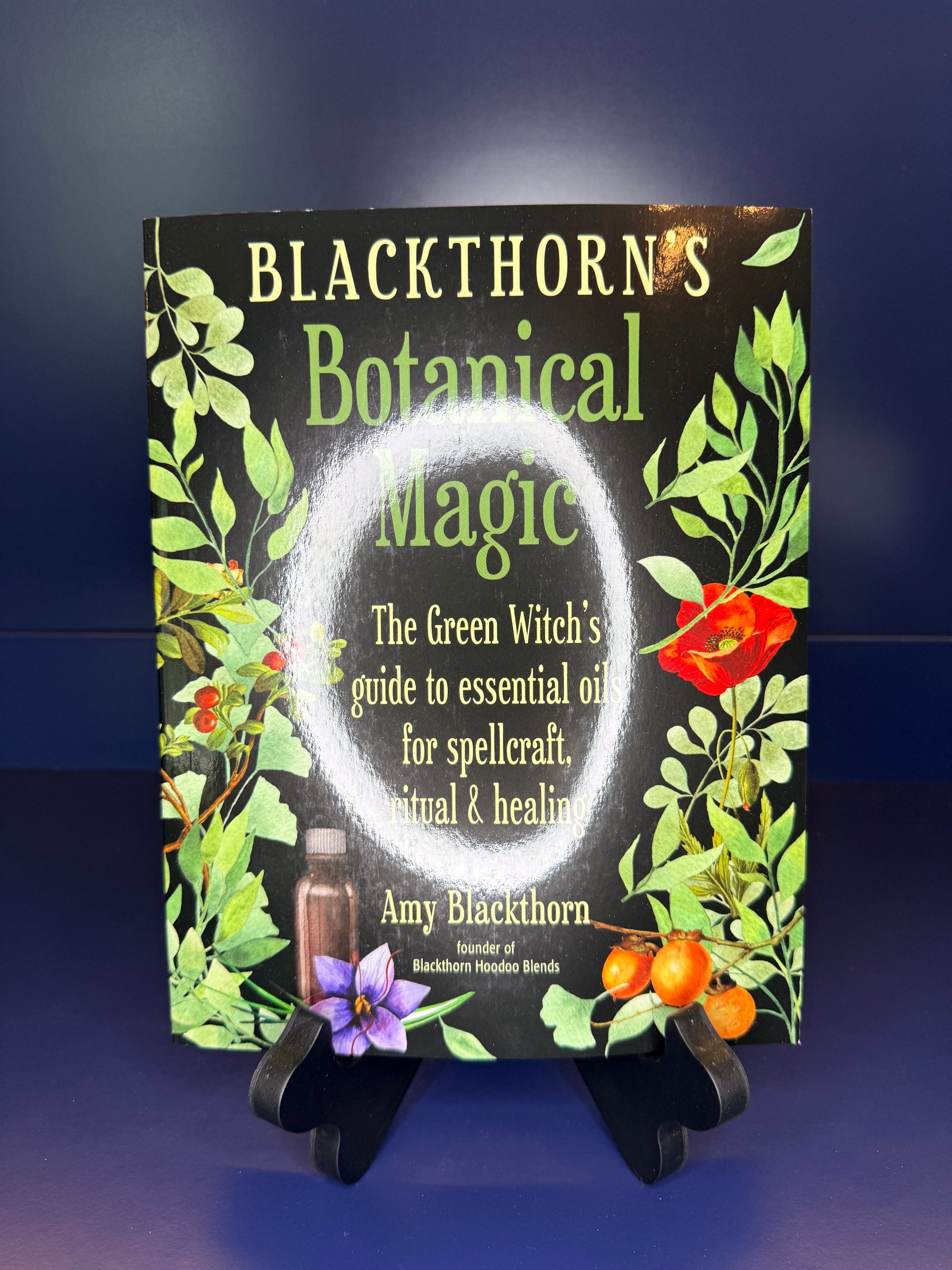 Book titled 'Blackthorn's Botanical Magic' on a stand with a dark background