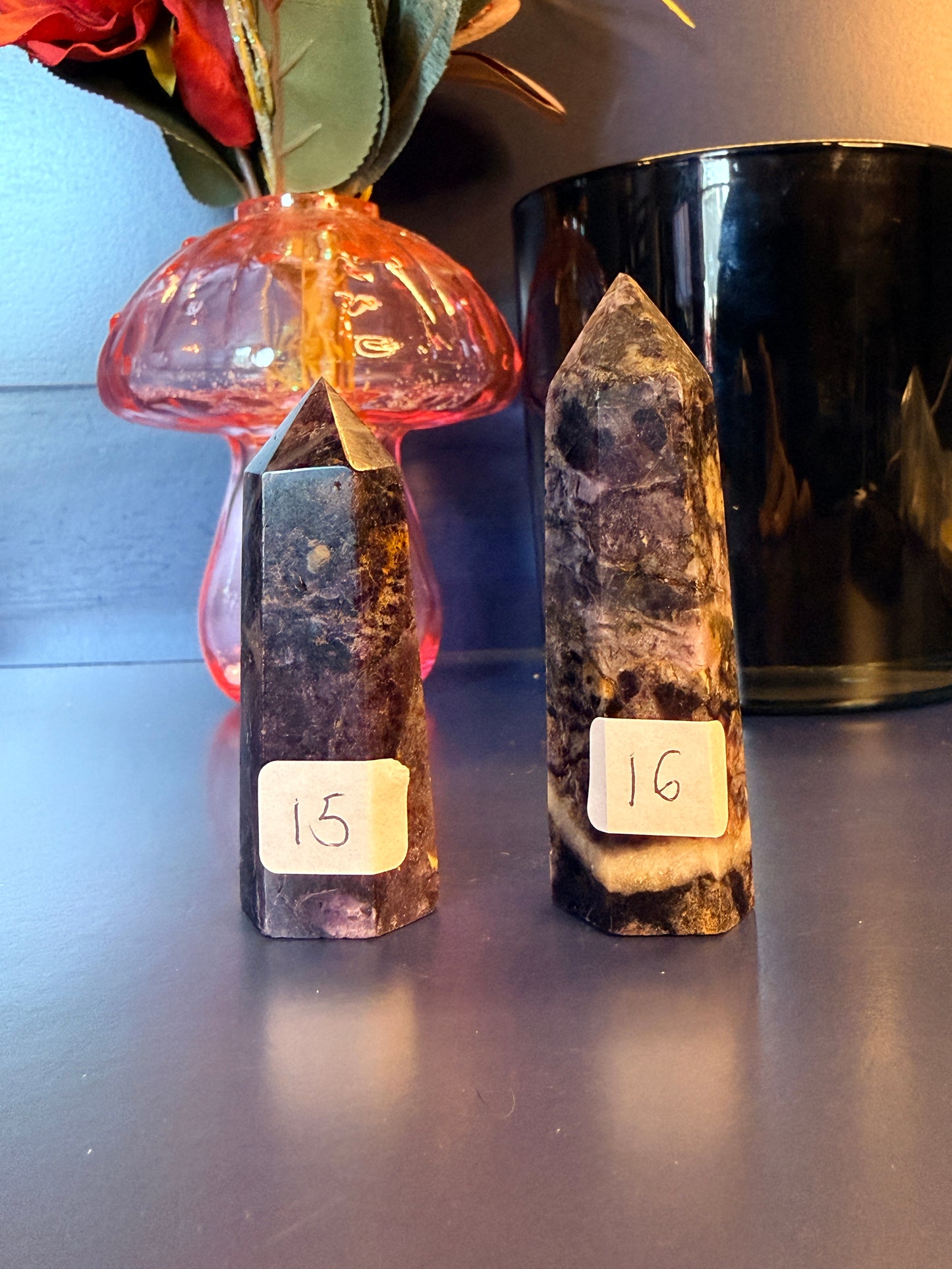Two purple crystal towers sitting in front of a glass mushroom and black jar