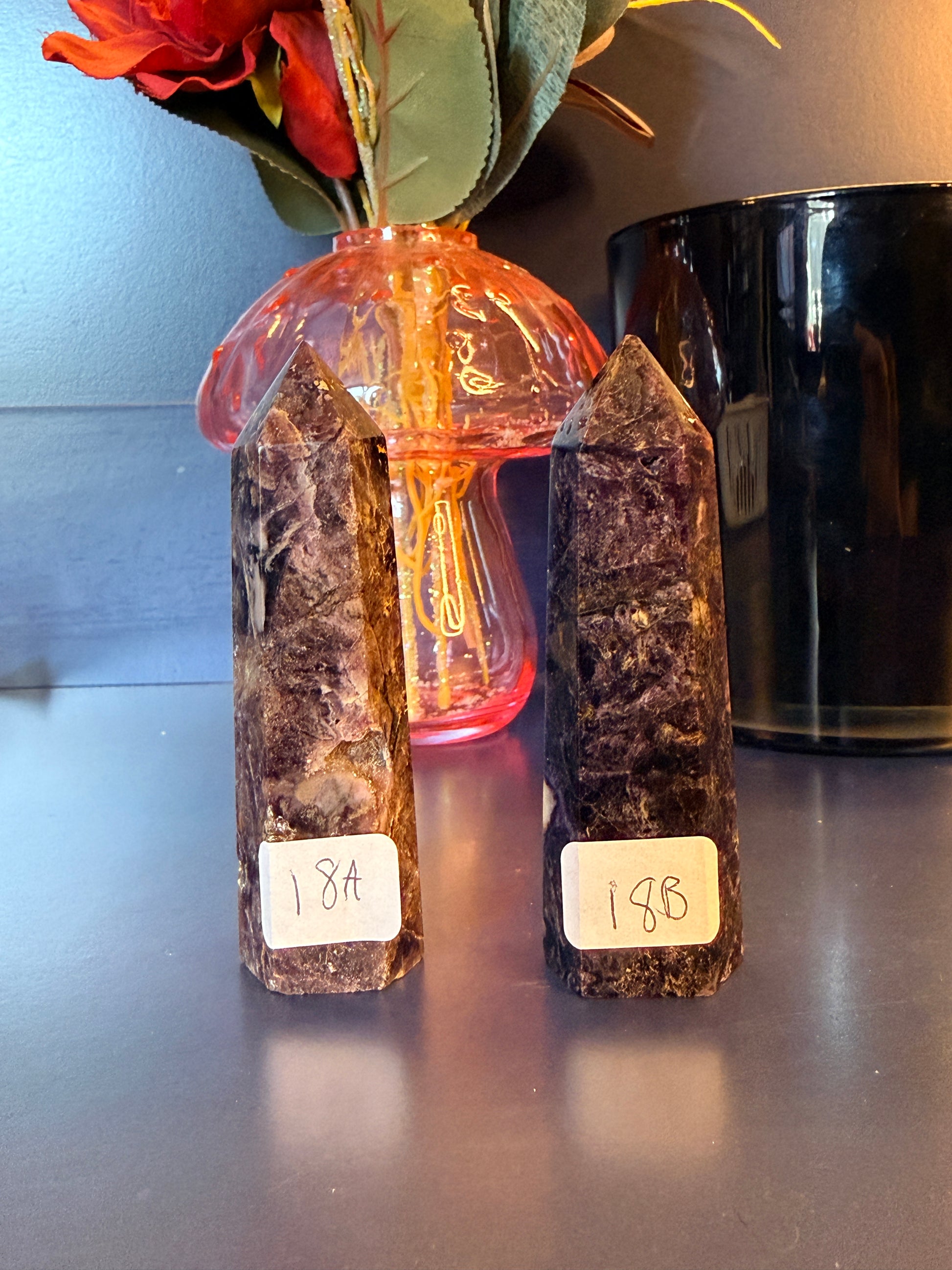 Two purple crystal towers sitting in front of a glass mushroom and black jar