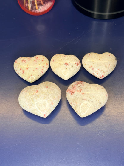 Five white and red speckled cinnabar hearts on a blue background