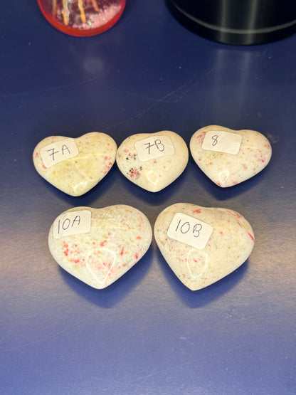 Five white and red speckled cinnabar hearts with numbered labels on a blue background