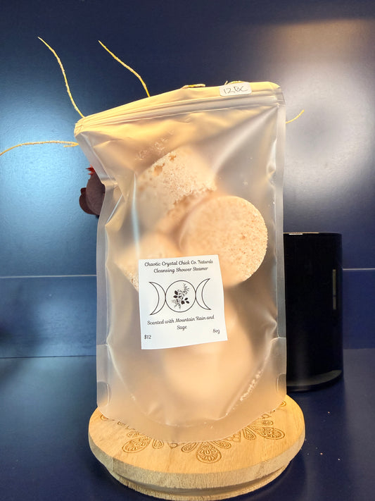 Packaged orange shower steamers on a decorative wooden coaster on a blue background