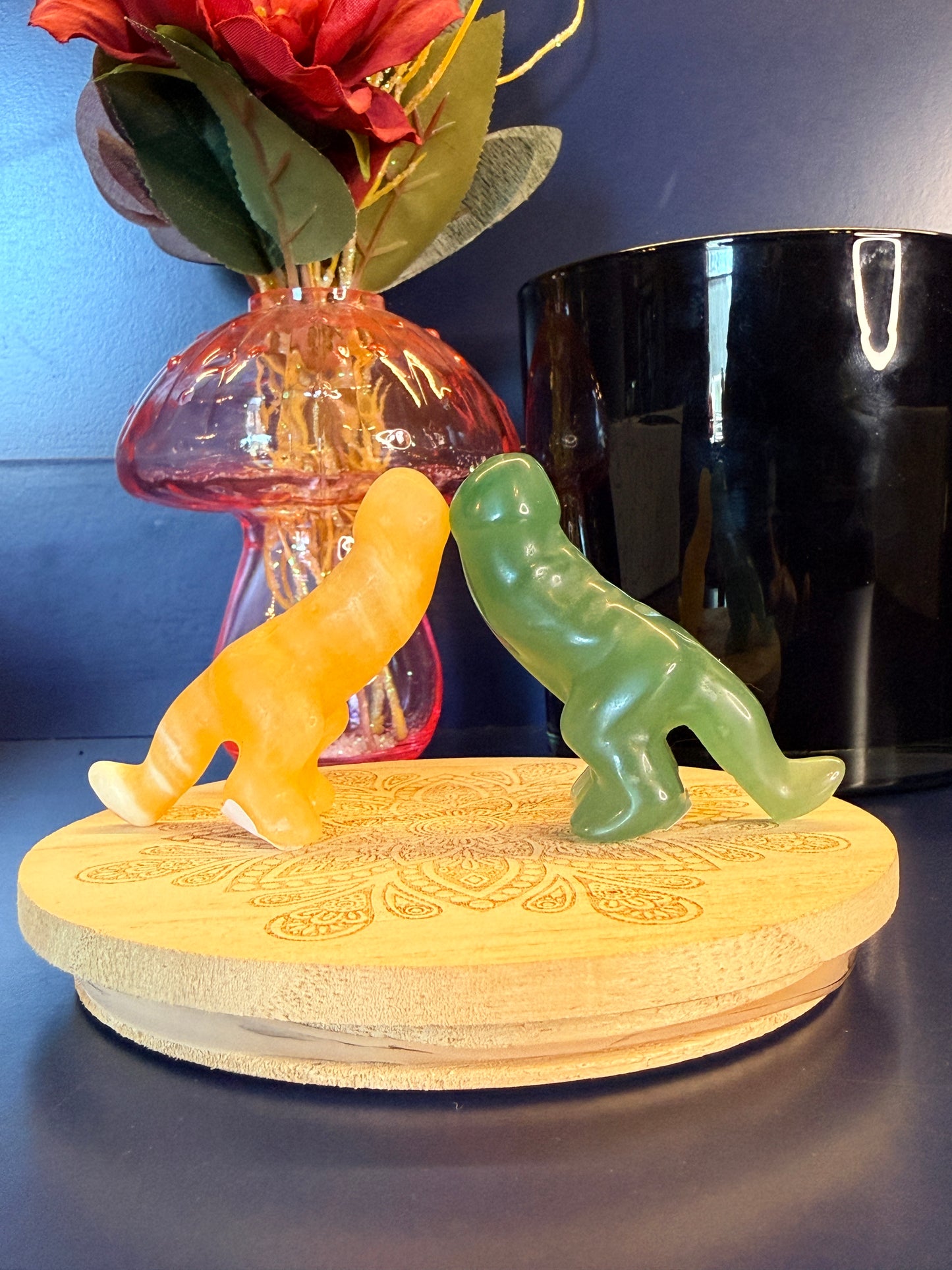 Two crystals, orange and green, sitting in front of a mushroom vase and black jar