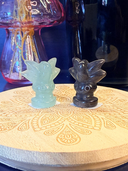Two crystal oddish sitting on a decorative wooden coaster in front of a glass mushroom and black jar