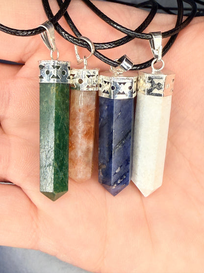 Hand holding four differently colored crystal pendants on nylon chains