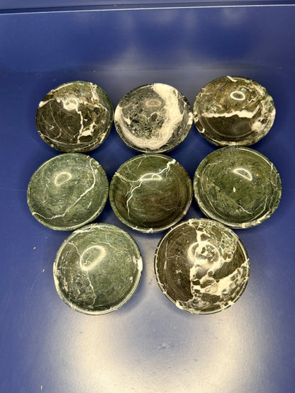 Eight dark green and white green onyx bowls on a blue background