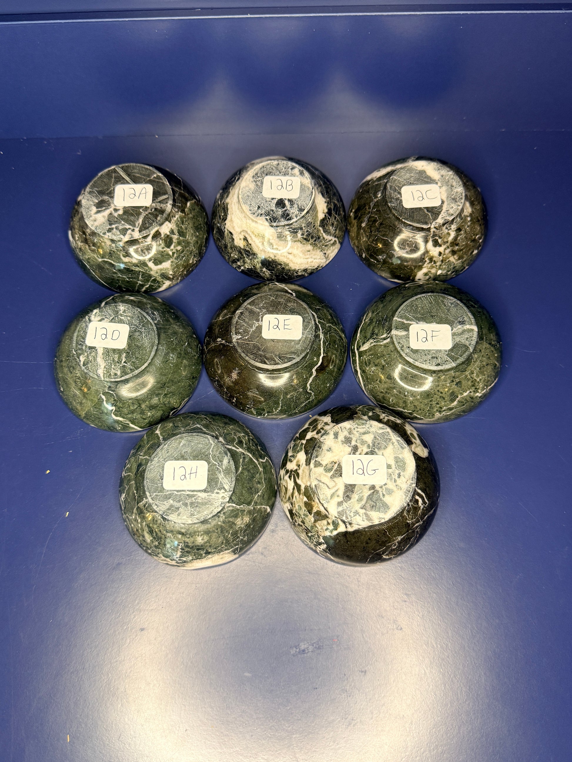 Eight dark green and white green onyx bowls with labels on a blue background