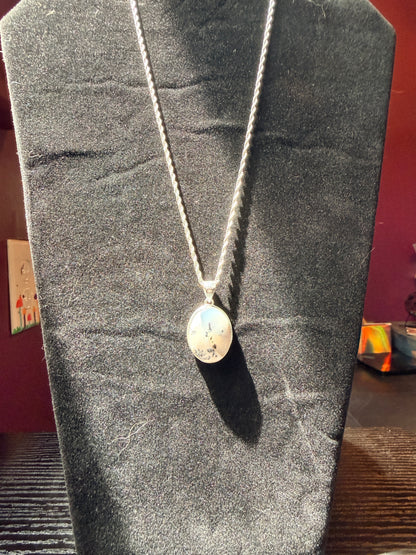 Sterling silver necklace resting on a black velvet jewelry stand holding an ovular dendrite agate pendant