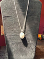 Sterling silver necklace resting on a black velvet jewelry stand holding an ovular dendrite agate pendant