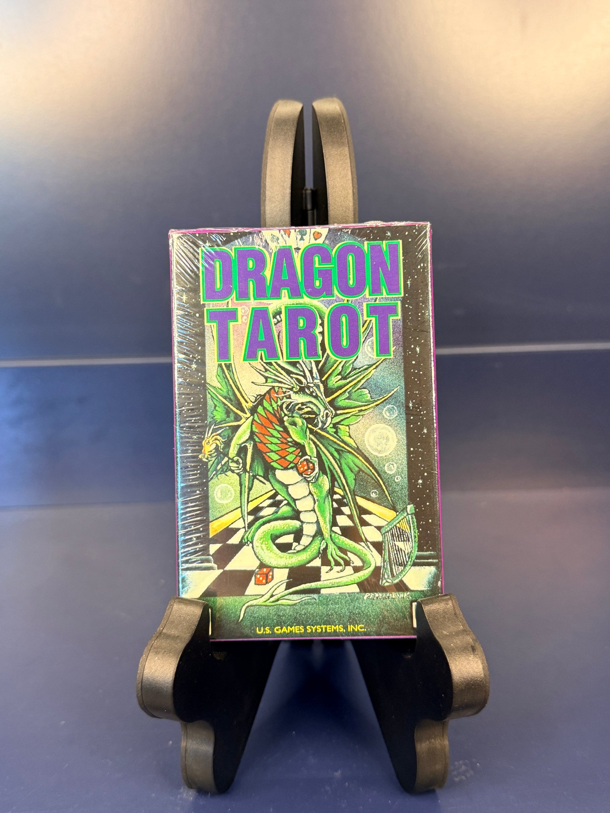 Dragon Tarot card deck on a black stand against a blue background