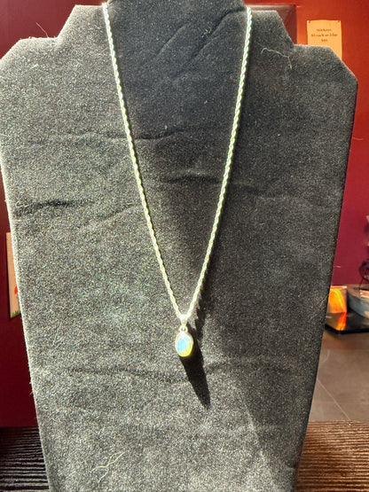 Sterling silver chain on a black velvet jewelry stand holding an ovular opal pendant