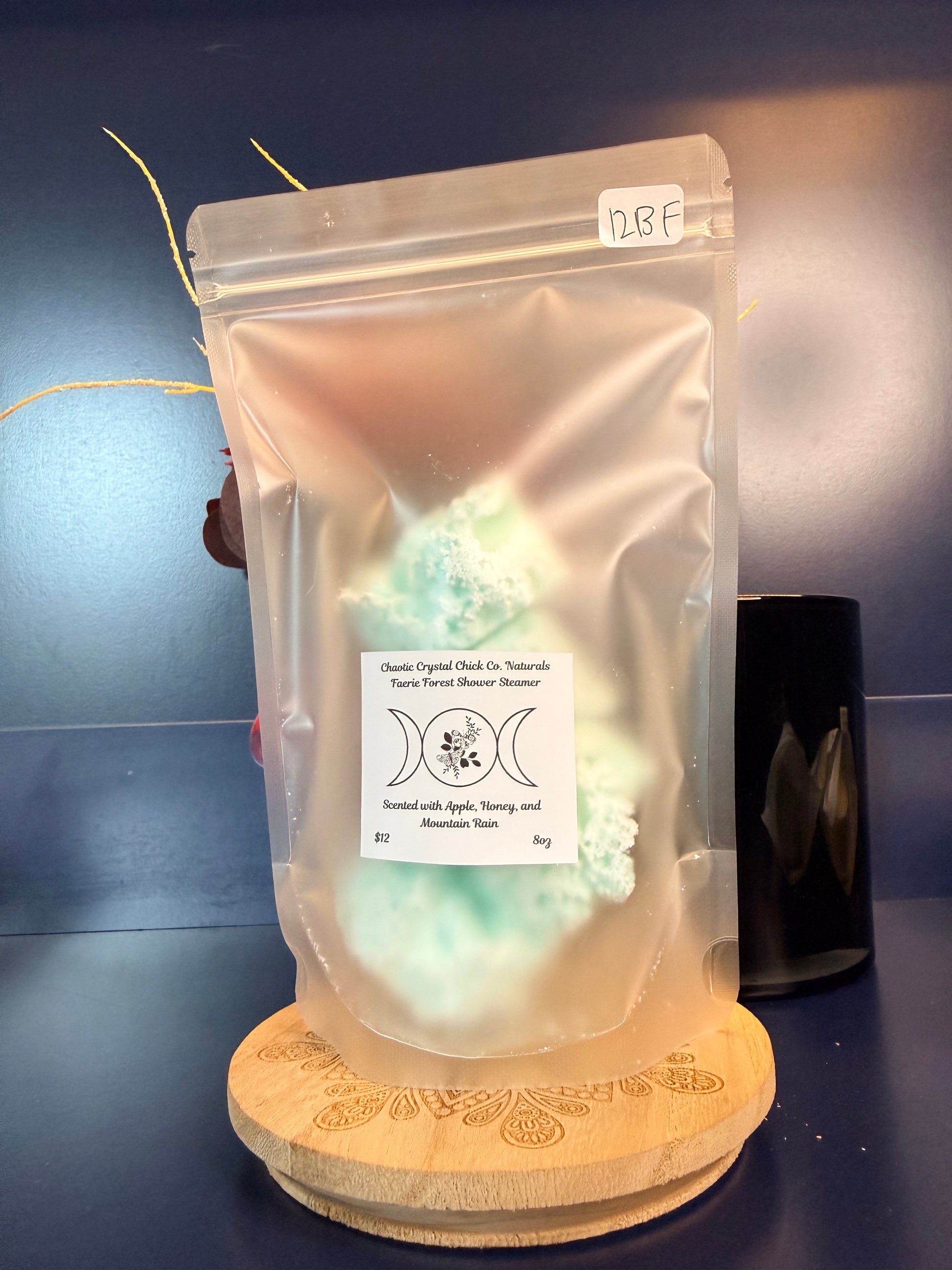 Packaged green shower steamers on a decorative wooden coaster on a blue background