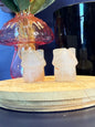 Two pale crystal houses sitting on front of a mushroom vase and black jar