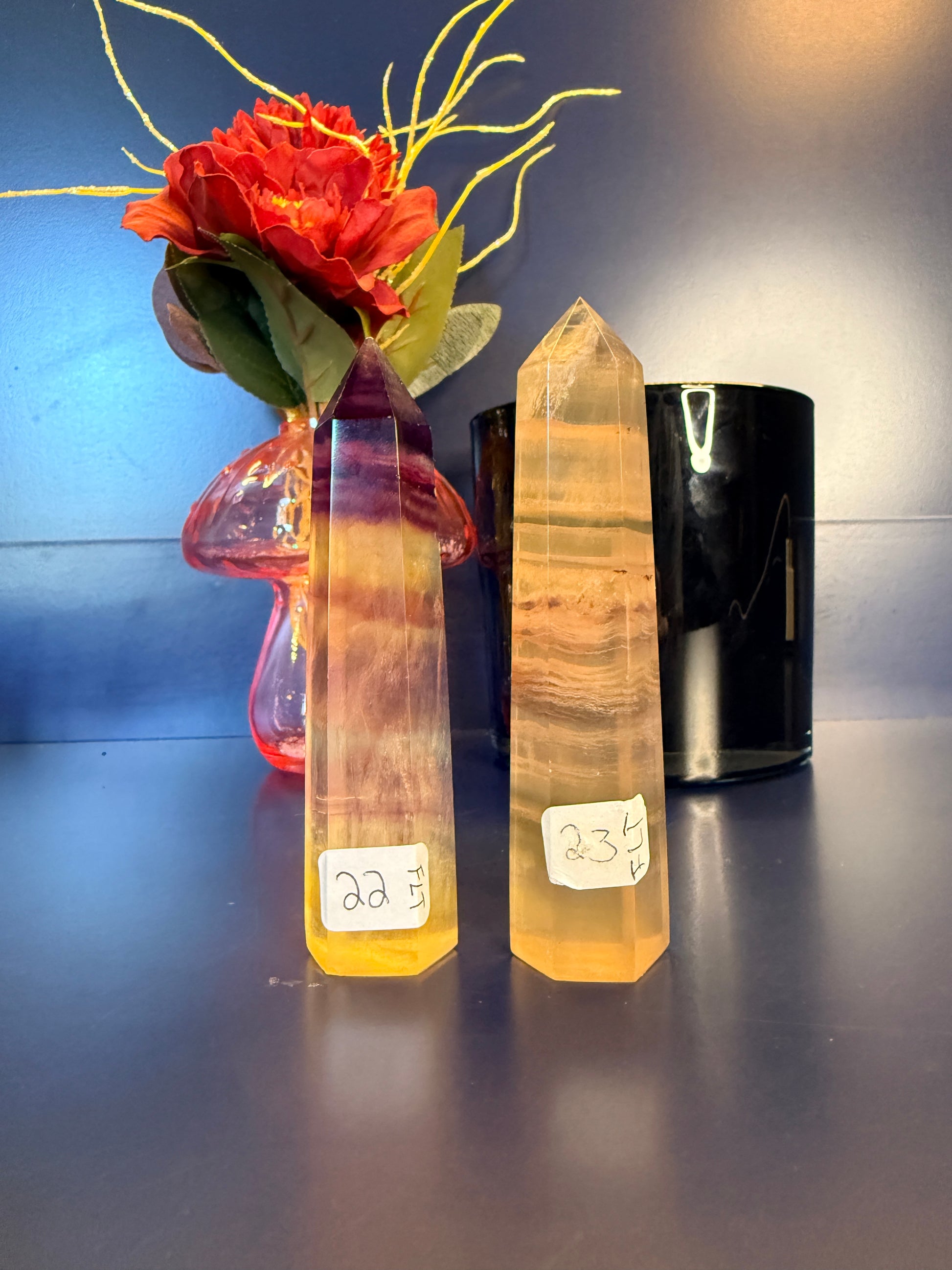 Two fluorite towers with labels on a reflective surface next to a decorative flower.