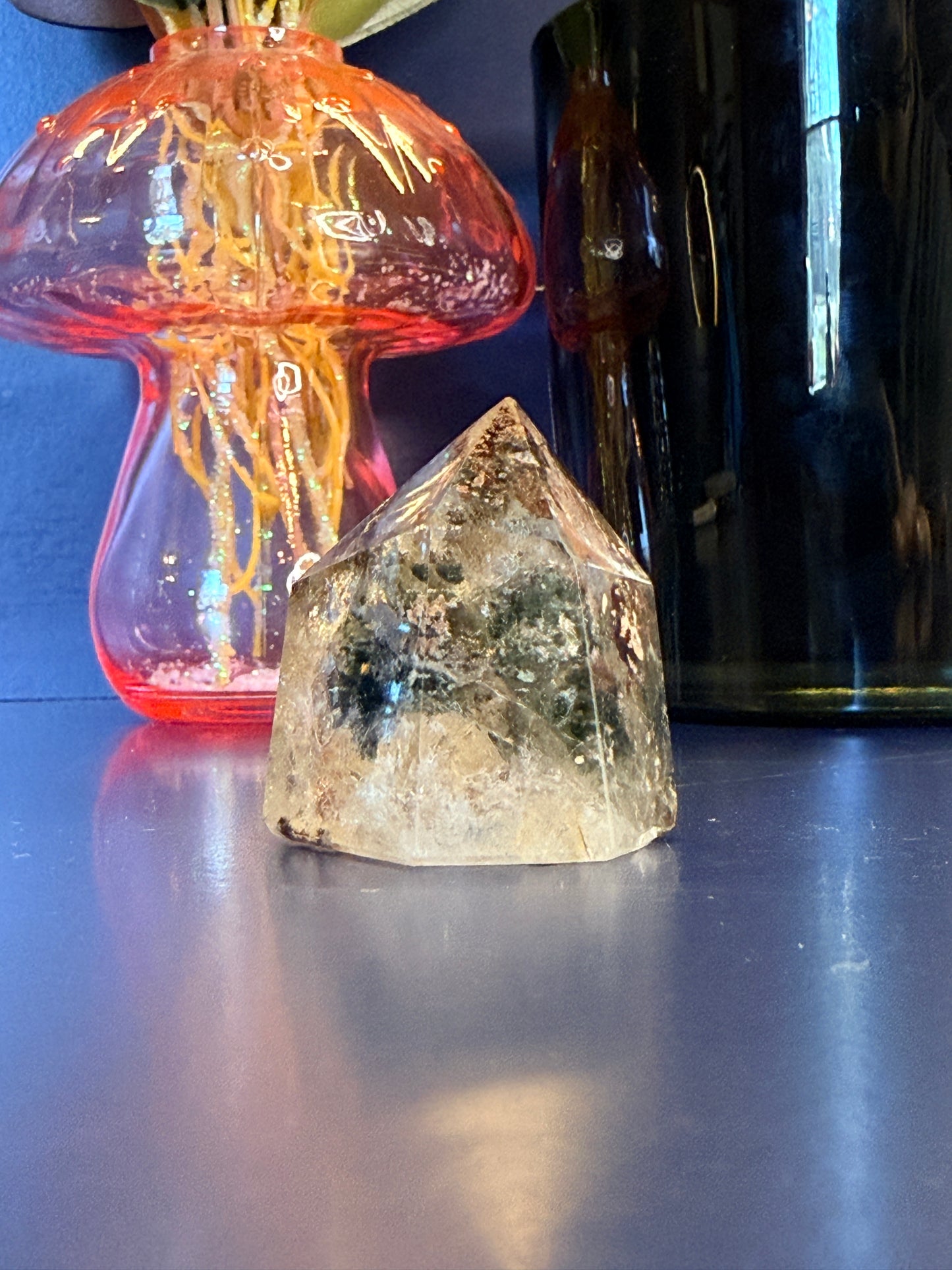 Small green and white crystal tower in front of a mushroom vase and black jar