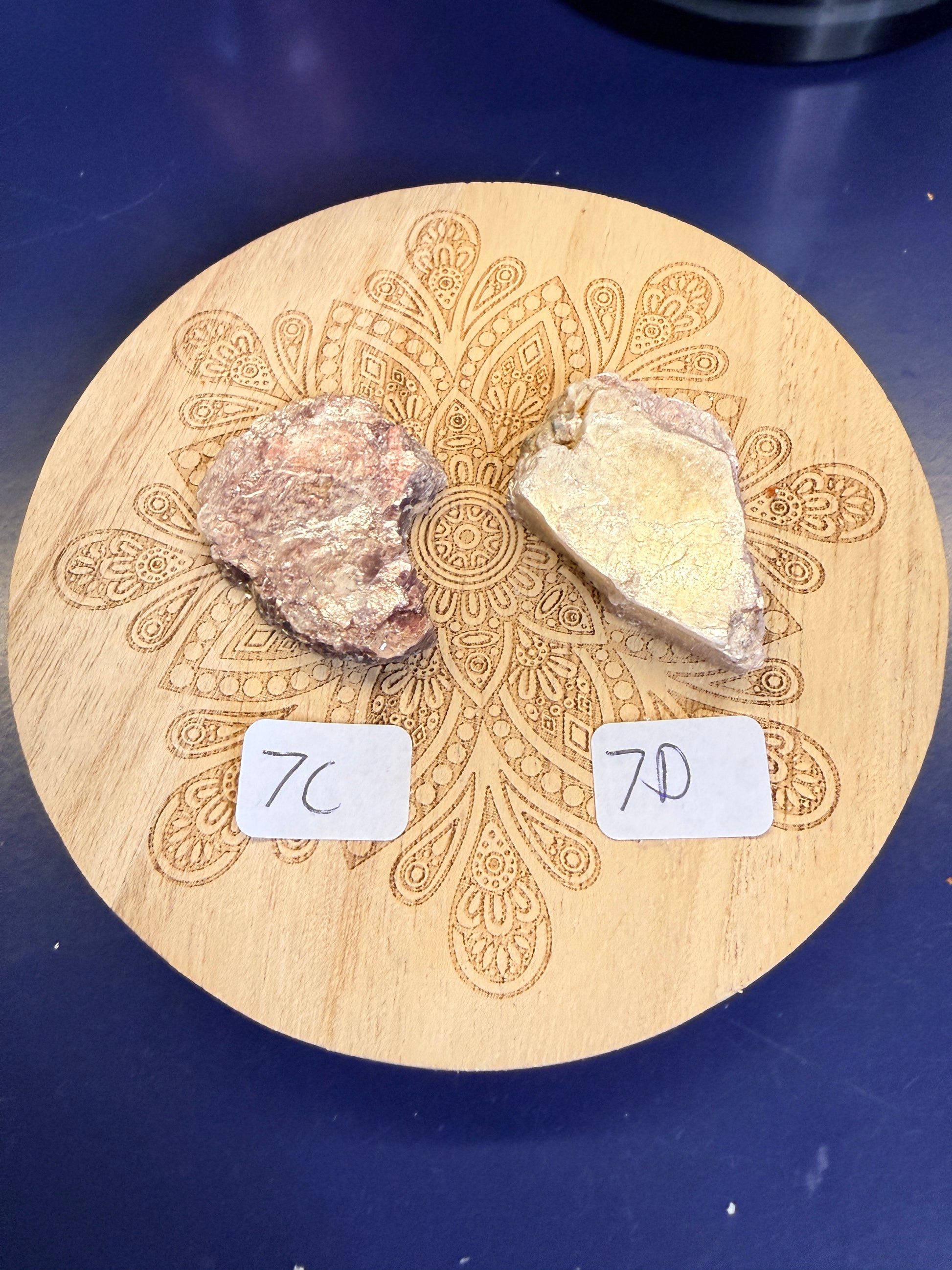 Two purple lepidolite pieces on a decorative wooden coaster on a blue background
