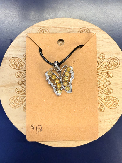 Butterfly shaped crystal pendant sitting on a decorative wooden coaster against a blue background