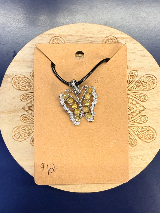 Butterfly shaped crystal pendant sitting on a decorative wooden coaster against a blue background