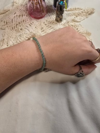 Green beaded crystal bracelet on a wrist with a white background