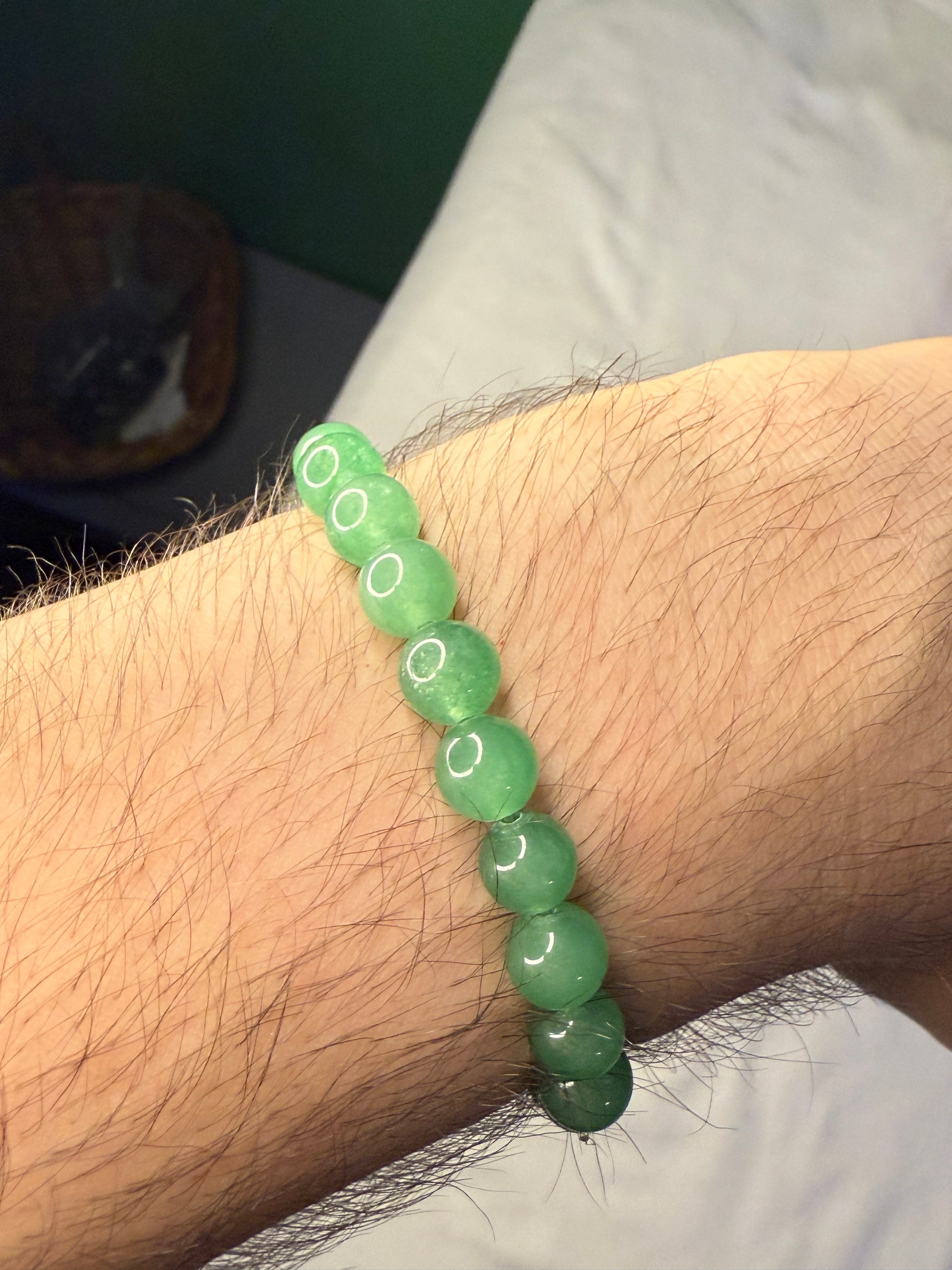 Green beaded crystal bracelet on a wrist with a blurred background