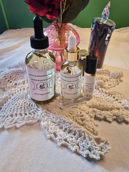 Three glass bottles filled with clear body oil with herbs on a white crochet mat and white table cloth