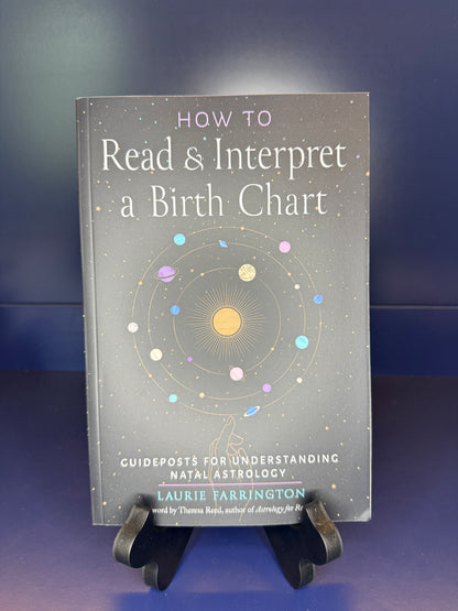 Book titled 'How to Read & Interpret a Birth Chart' by Laurie Farrington on a stand against a dark background