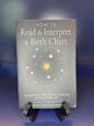 Book titled 'How to Read & Interpret a Birth Chart' by Laurie Farrington on a stand against a dark background