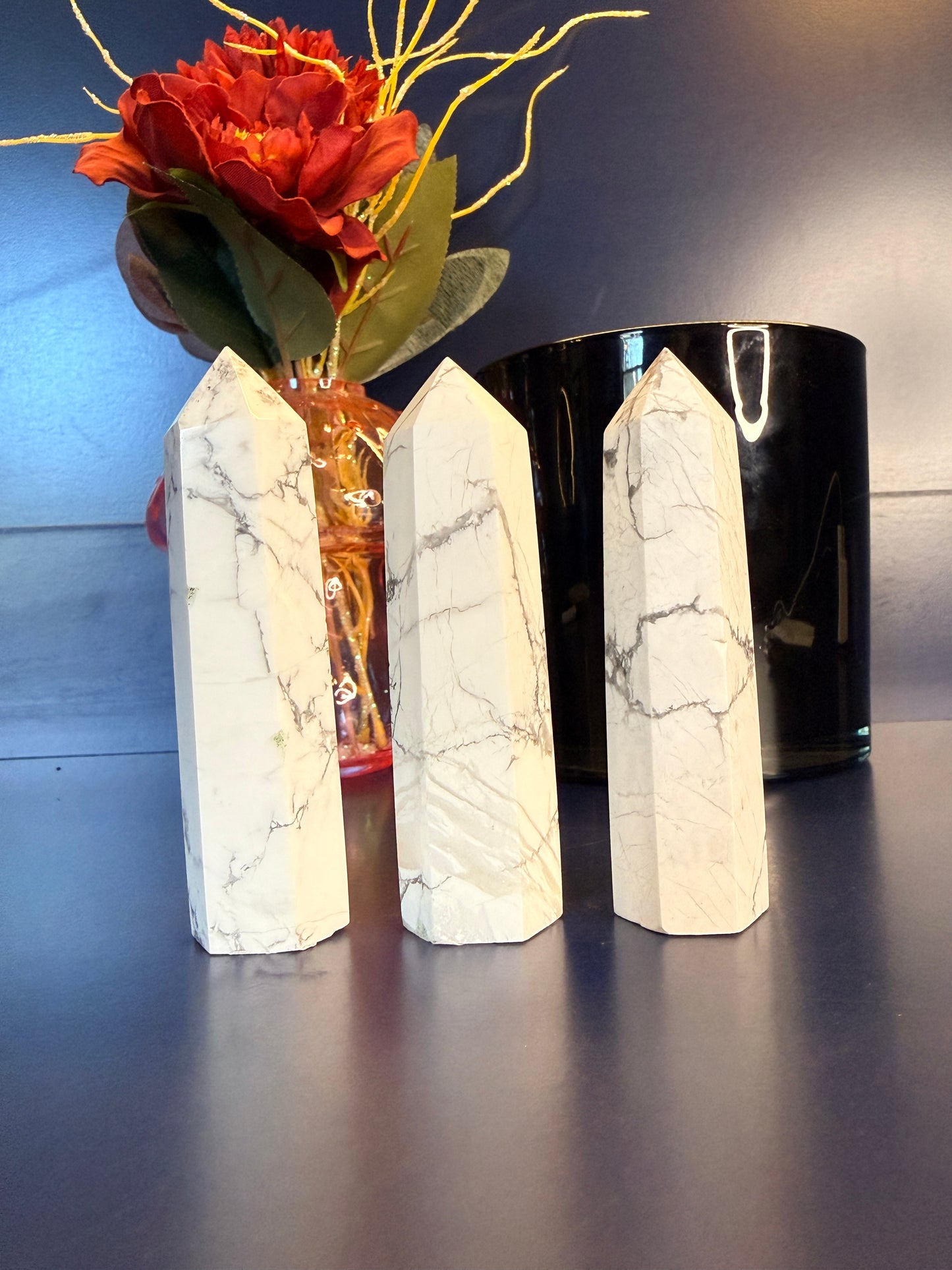 Three white marbled crystal towers in front of a flower vase and black jar