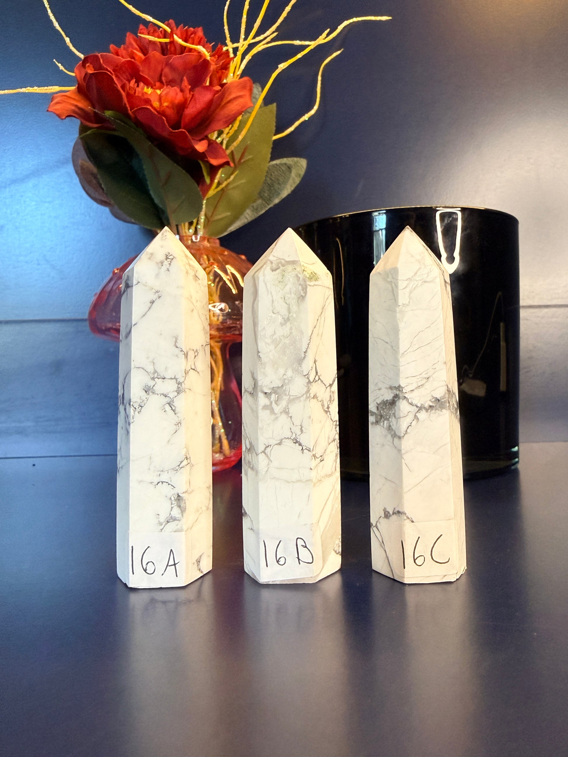 Three white marbled crystal towers in front of a flower vase and black jar