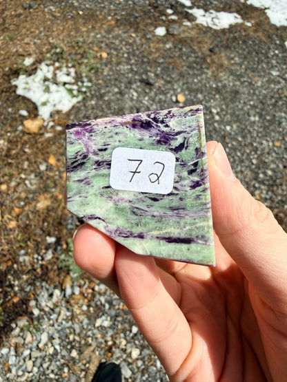 A purple and light green kammererite freeform with a "72" label in front of gravel