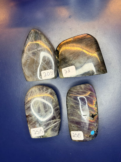 Four grey labradorite free forms with purple flash and numbered labels on a blue background
